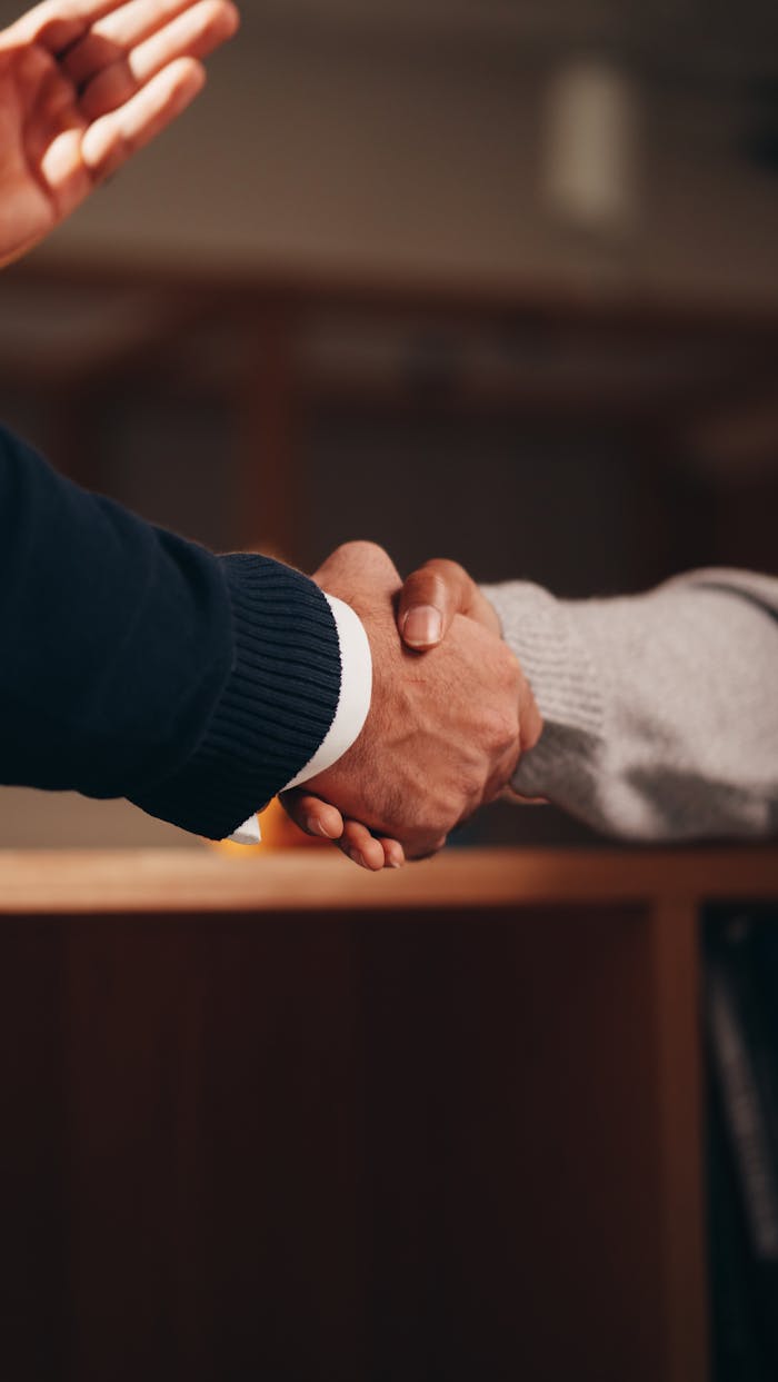 Two hands shaking in a professional setting, symbolizing business deal or agreement.
